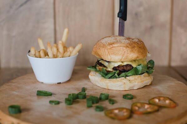 A burger with fries on a wooden board.
