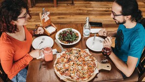 A wooden dining table with a pizza, salad, and drinks. - Valle Escondido Nature Reserve Hotel & Farm (Monteverde)