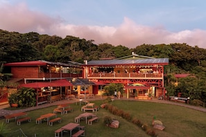 A two-story building with a balcony, outdoor seating, and a grassy area. - Valle Escondido Nature Reserve Hotel & Farm (Monteverde)