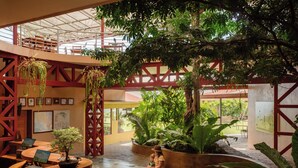 A spacious indoor area with a curved bench, potted plants, and a high ceiling with structural beams. - Valle Escondido Nature Reserve Hotel & Farm (Monteverde)