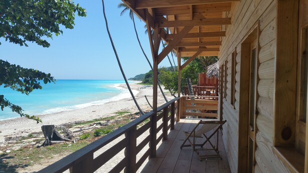 A wooden cabin with a balcony overlooking a beach. - Hotel SeaBreeze (Paraiso)