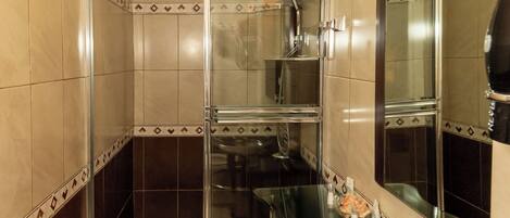 Un baño moderno con lavamanos de vidrio, cabina de ducha y un espejo grande.