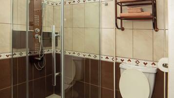 Une salle de bain avec une douche à parois de verre, des toilettes et un porte-serviettes.