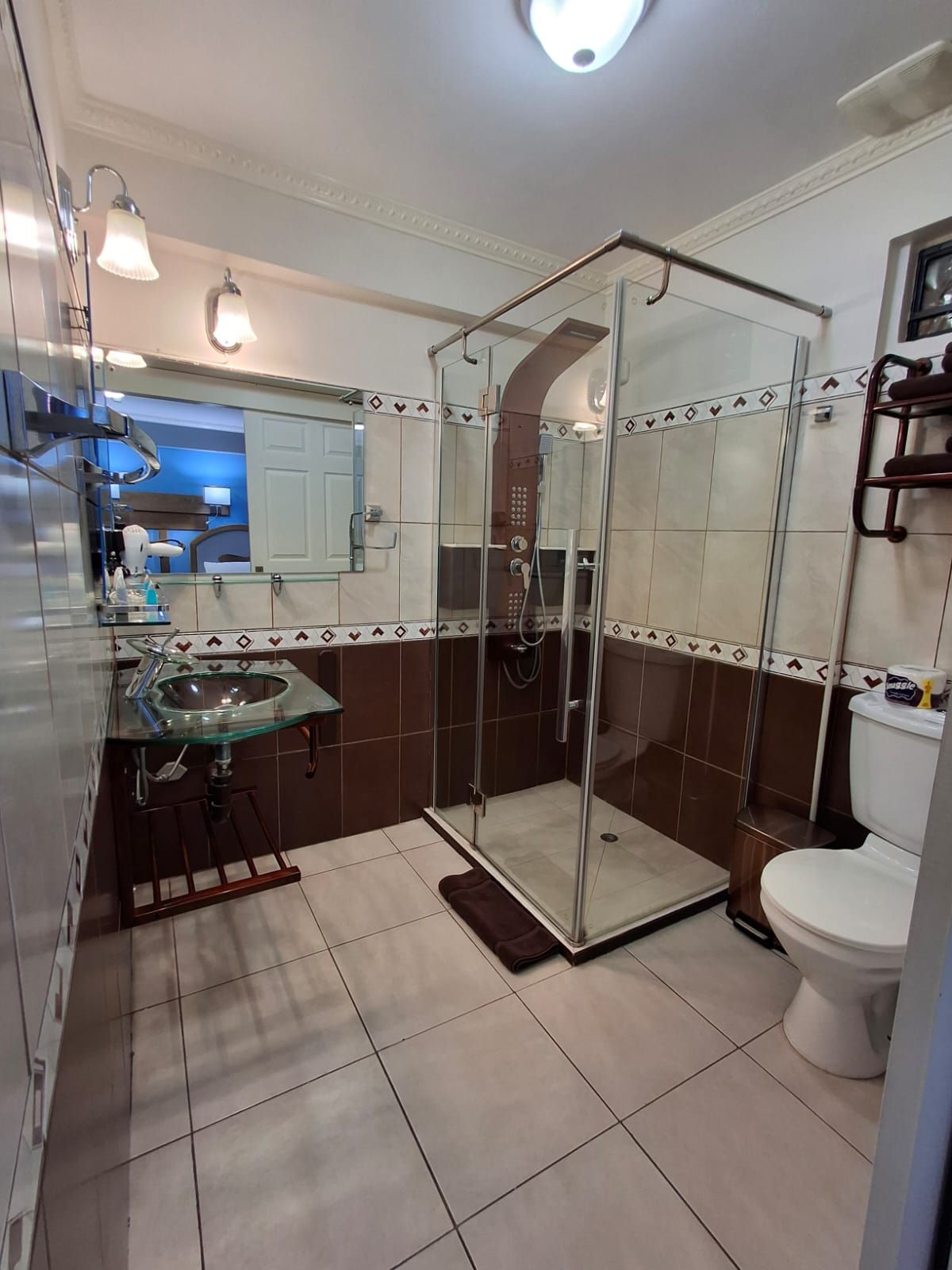 Une salle de bain avec une douche à parois de verre, un lavabo en verre et des toilettes.
