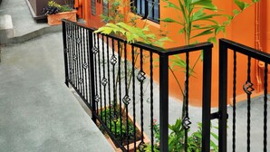 A two-story building with an orange facade, a black metal fence, and potted plants. - Culture Crossroads Inn (Port of Spain)