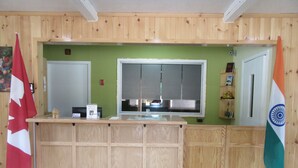 A reception area with a wooden counter, a large window, and two flags. - The Village Inn Motel (Huron Shores)