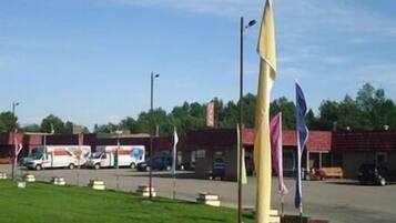 A parking lot with several flags, a building with a red roof, and a white van in the background.