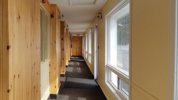 A narrow hallway with wooden walls and large windows on one side. - The Village Inn Motel (Huron Shores)
