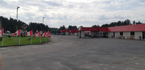 A large parking lot with a red-roofed building, flags, and a sign indicating a village.