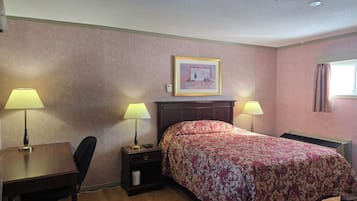 A hotel room with a bed, two bedside lamps, a desk with a chair, a nightstand, a framed picture on the wall, and a window with curtains.