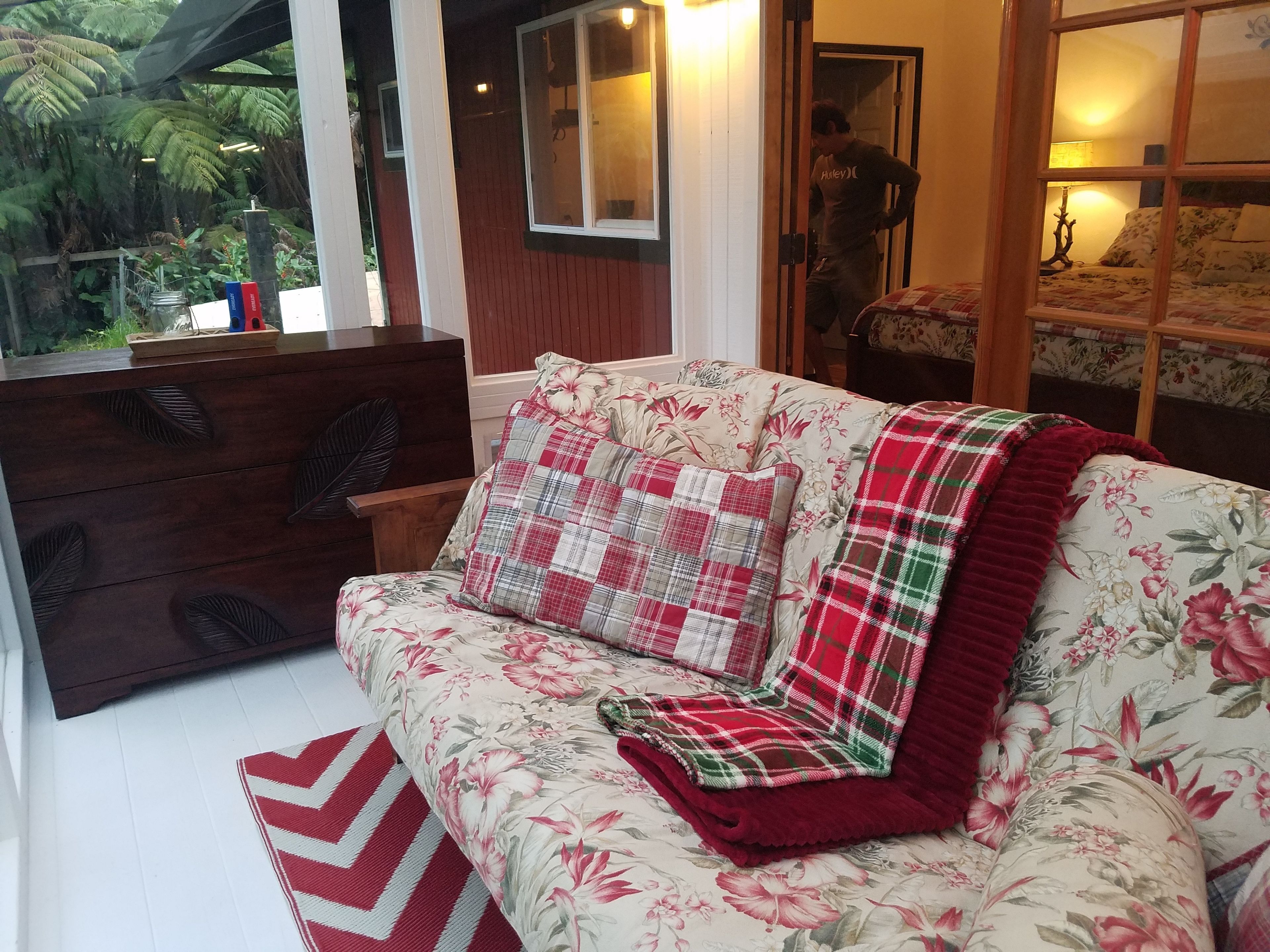 Ein gemütlicher Wohnbereich mit einem floralen Sofa, einem Holztisch und einem roten und weißen Zickzack-Teppich.
