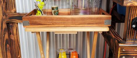 A rustic wooden table with a metal rack holding various glassware and a red bow decoration.
