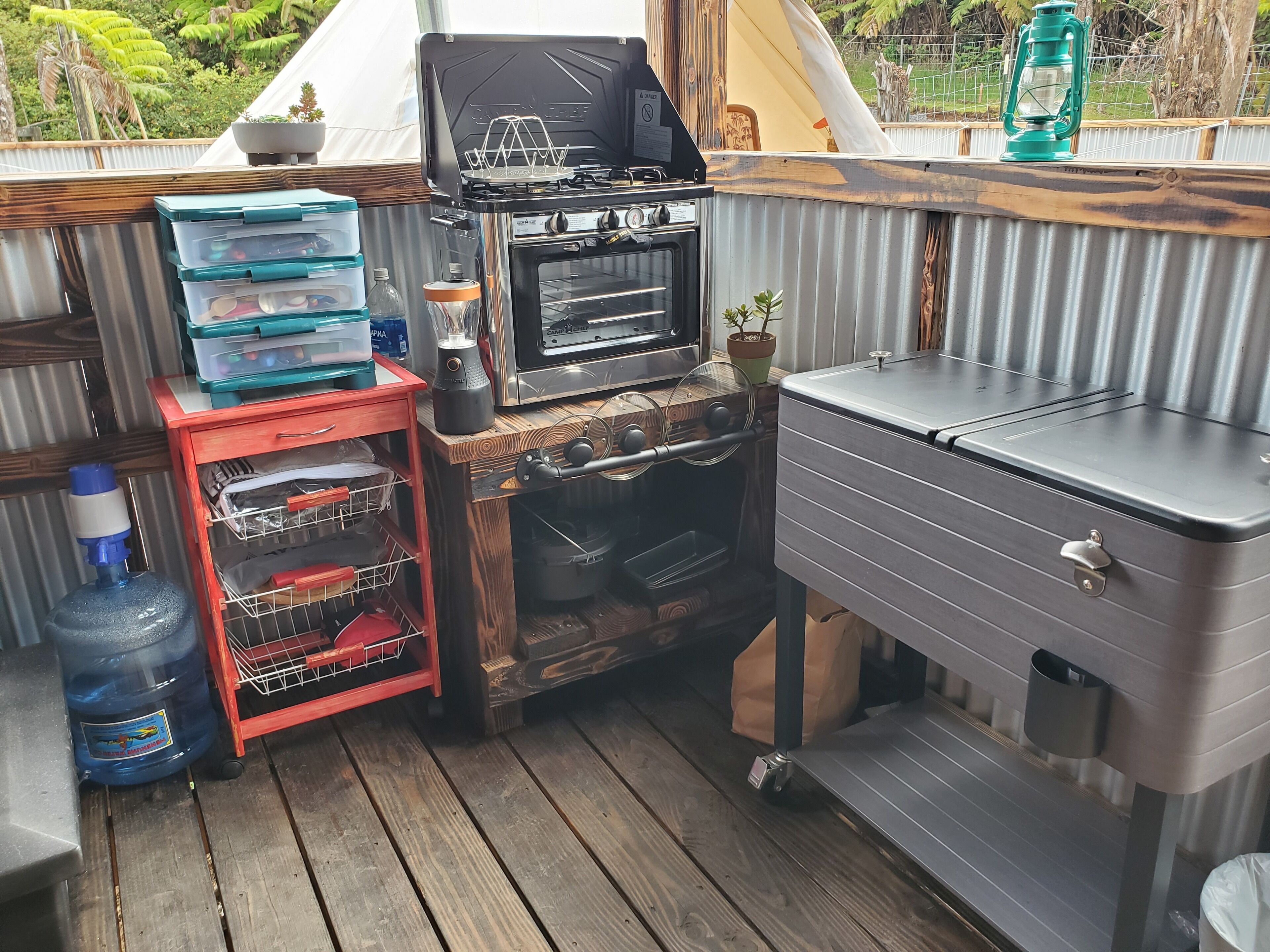 A compact outdoor kitchen with a gas stove, oven, and storage cabinets.