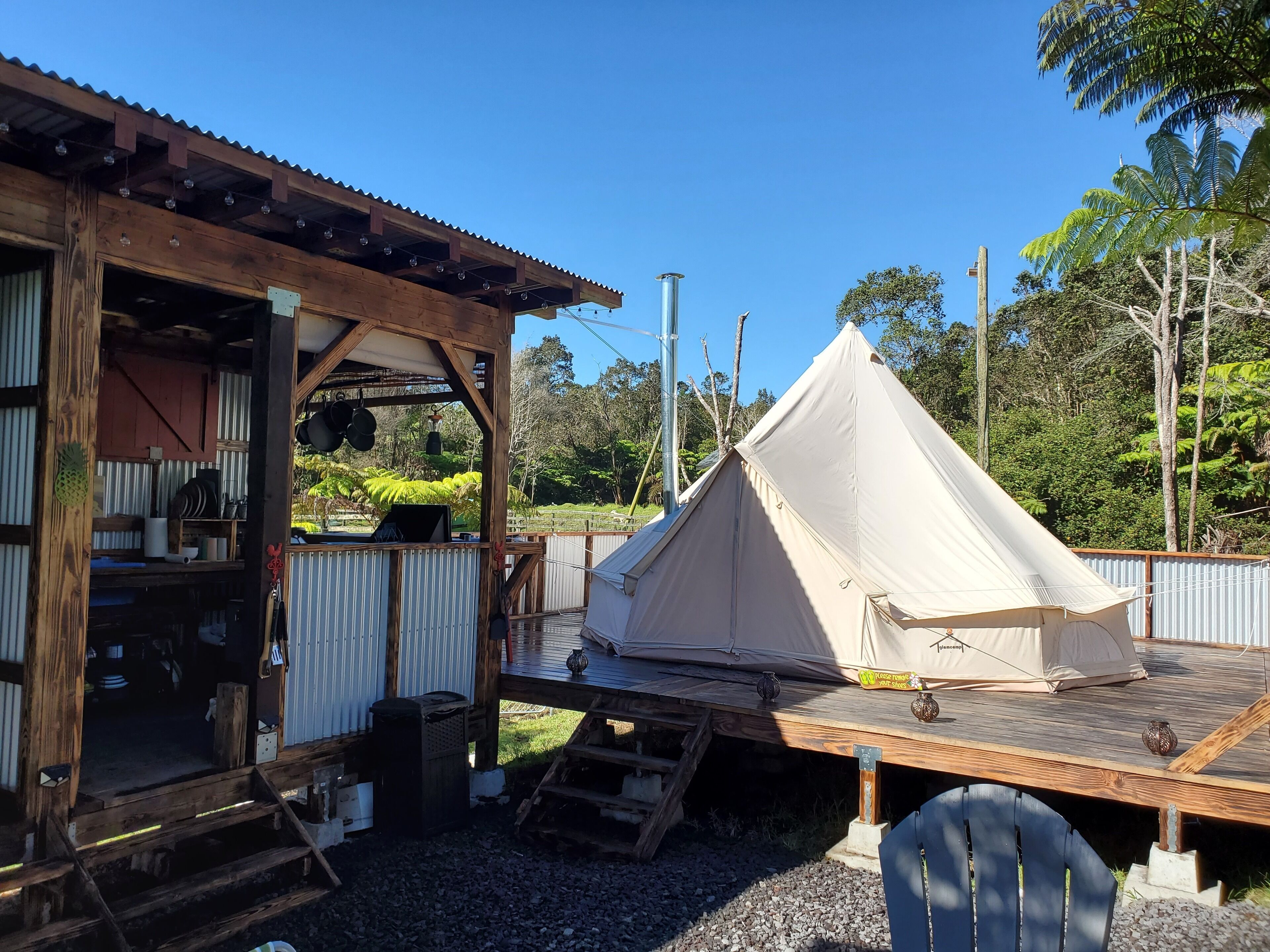 A rustic wooden building with a covered outdoor area and a large beige tent.