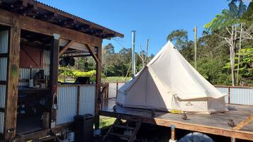 A rustic wooden building with a covered outdoor area and a large beige tent.