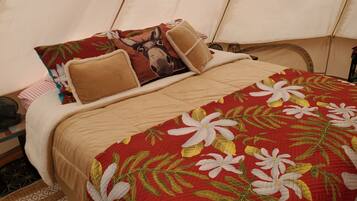 Een bed met een quilt met bloemenprint, twee kussens met een ezel ontwerp, en een vloerkleed met dessin.