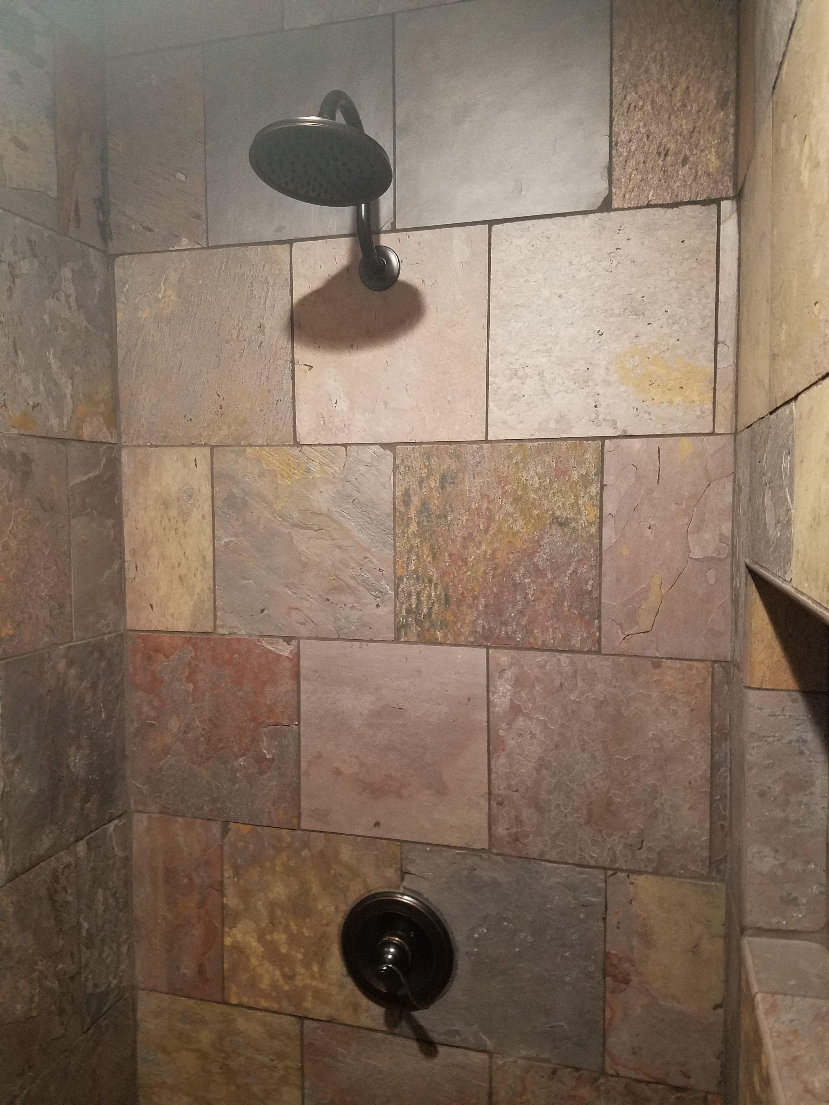A shower area with a handheld showerhead and a wall-mounted faucet.