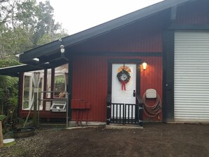 A red building with a white door, a black gate, and a wreath on the door.