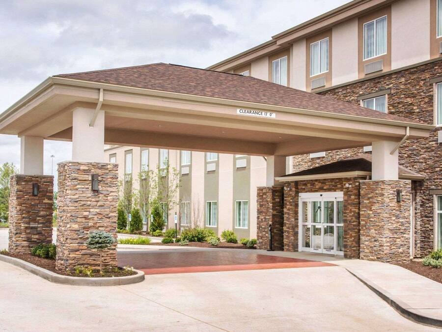 A hotel entrance with a covered walkway, stone pillars, and a clear signage indicating a clearance of 13 feet.