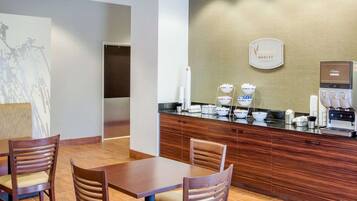 Un hall de hotel con una recepción, una máquina de café y un cartel en la pared que dice "Medley".