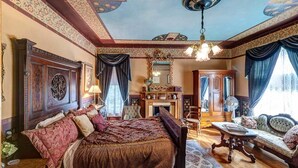 Een kamer met een groot bed, een zithoek met een bank en een tafel, en een open haard.
