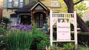 Een gebouw met een bord waarop 'Manderley Bed & Breakfast Inn' staat en een melding dat 'Reserveringen vereist' is.
