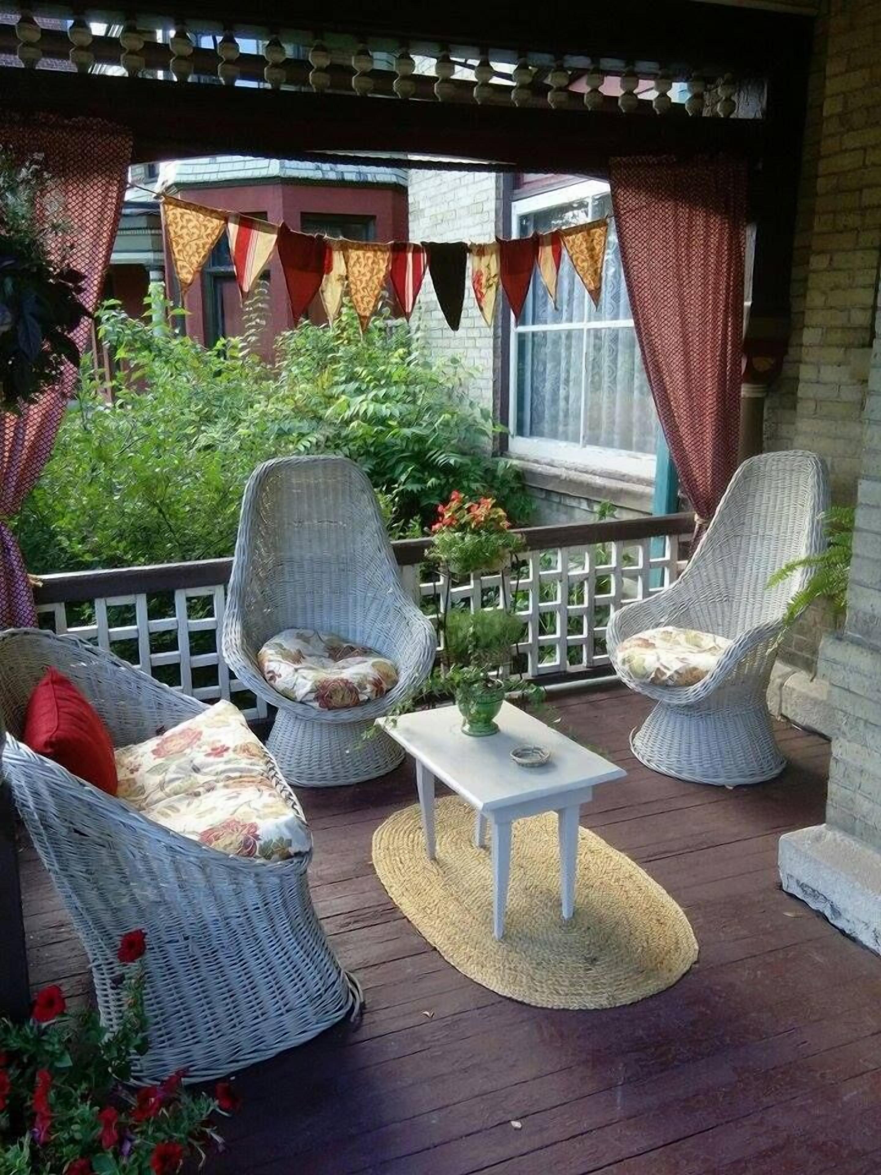 A covered outdoor seating area with wicker furniture and a small table.