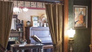 Een kamer met een houten vloer, een kroonluchter, een tafel met een lamp en een stoel.