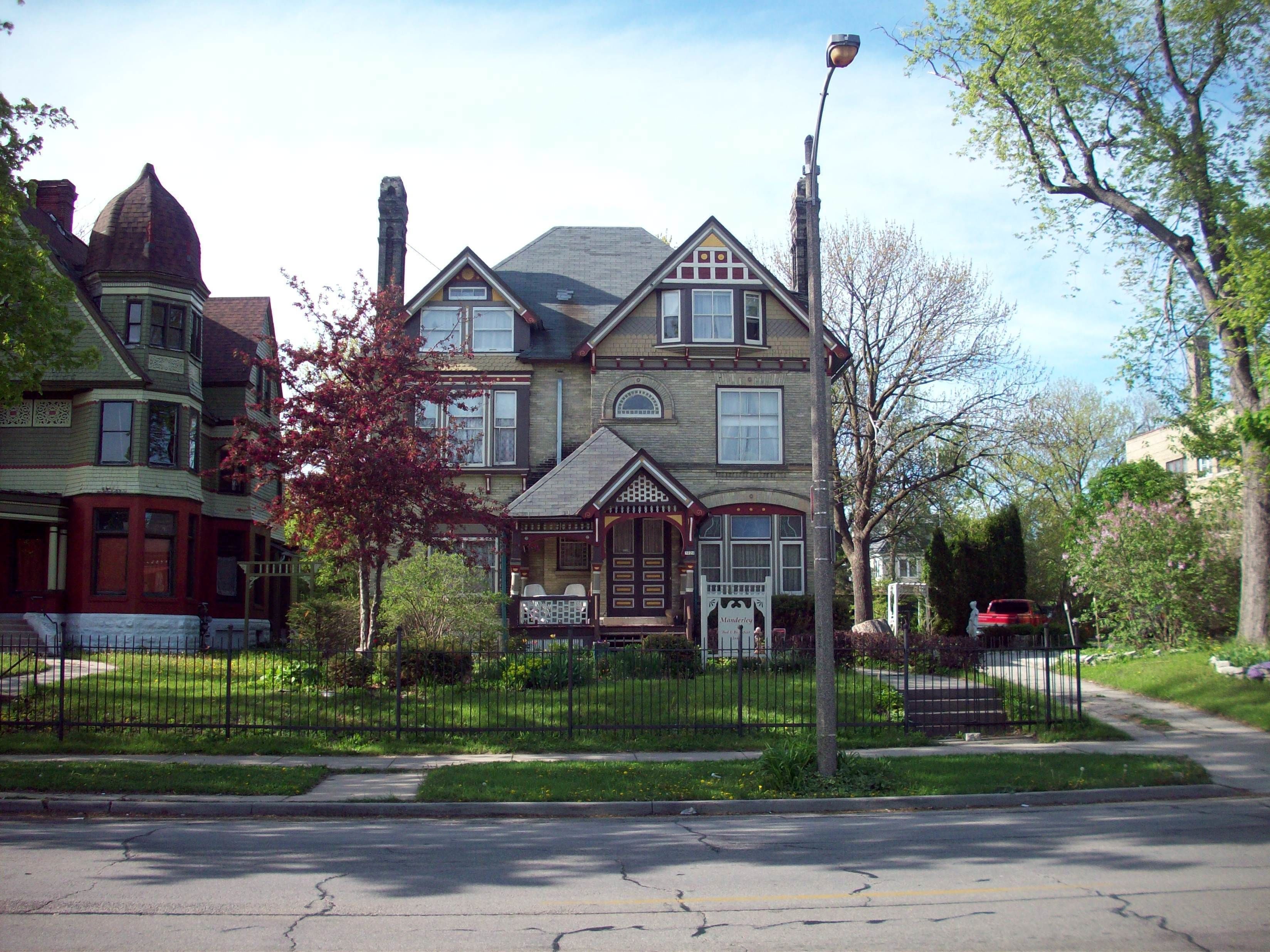 A Victorian-style house with a prominent bay window, a front porch, and a well-maintained lawn.