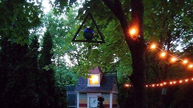 Een gezellig buiten zitgedeelte met stenen meubels en een kleine tafel, omringd door weelderige begroeiing en lichtjes.