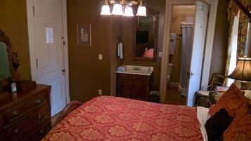 A bedroom with a bed, dresser, and a bathroom visible through an open door.