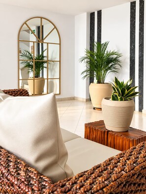 A modern living room with a sofa, a coffee table, and potted plants. - Hotel Sicarare (Valledupar)
