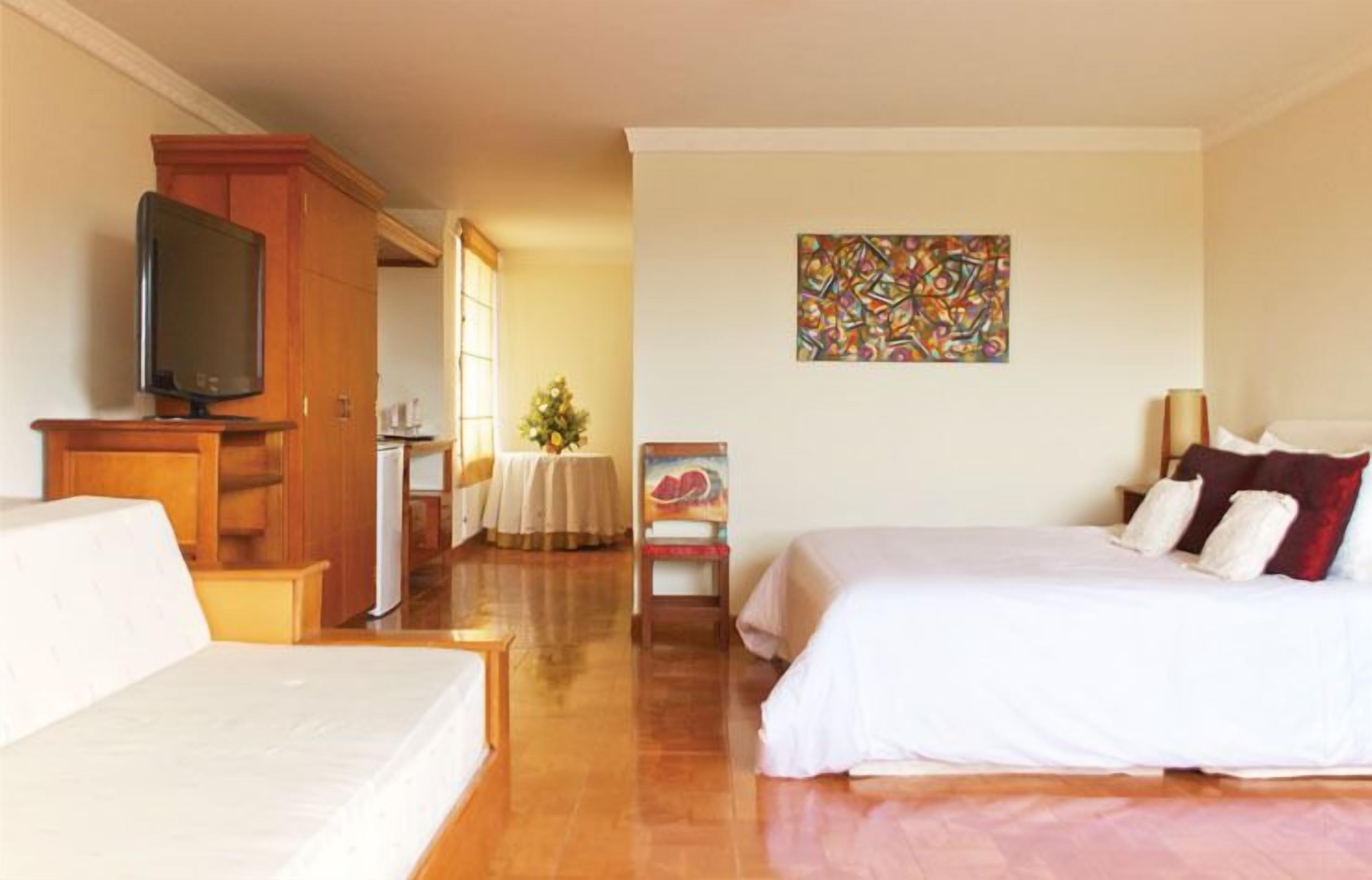 Ein Hotelzimmer mit Bett, Fernseher, Schreibtisch und Stuhl.