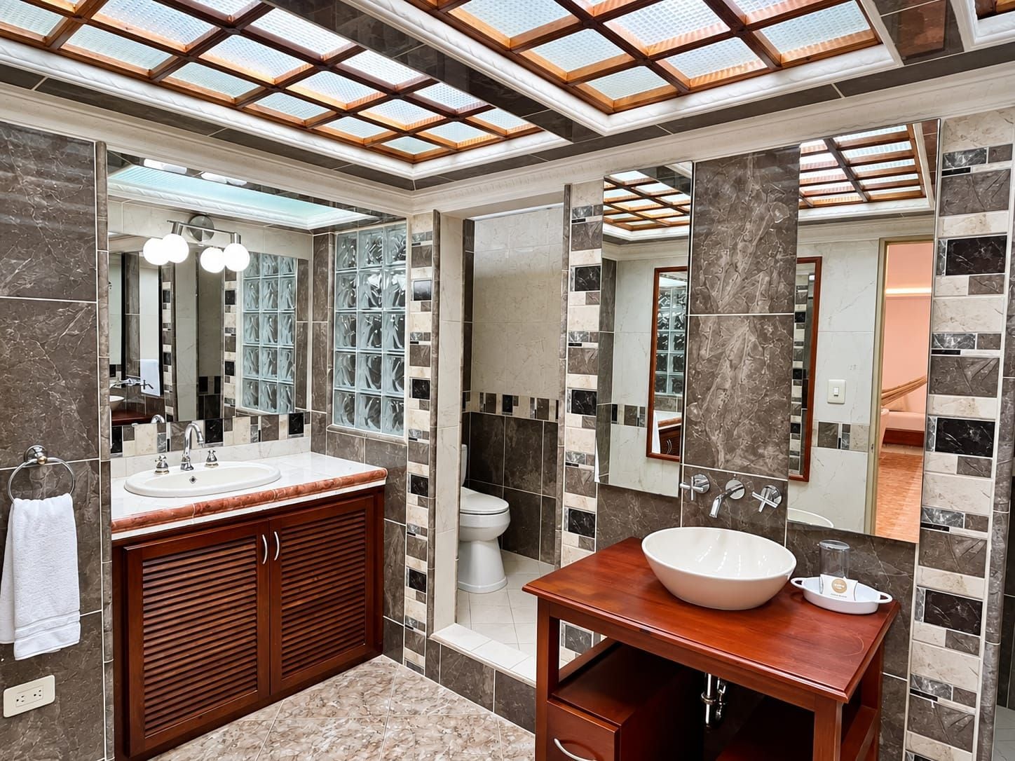 A modern bathroom with a large mirror, a vanity with a bowl sink, and a shower area.