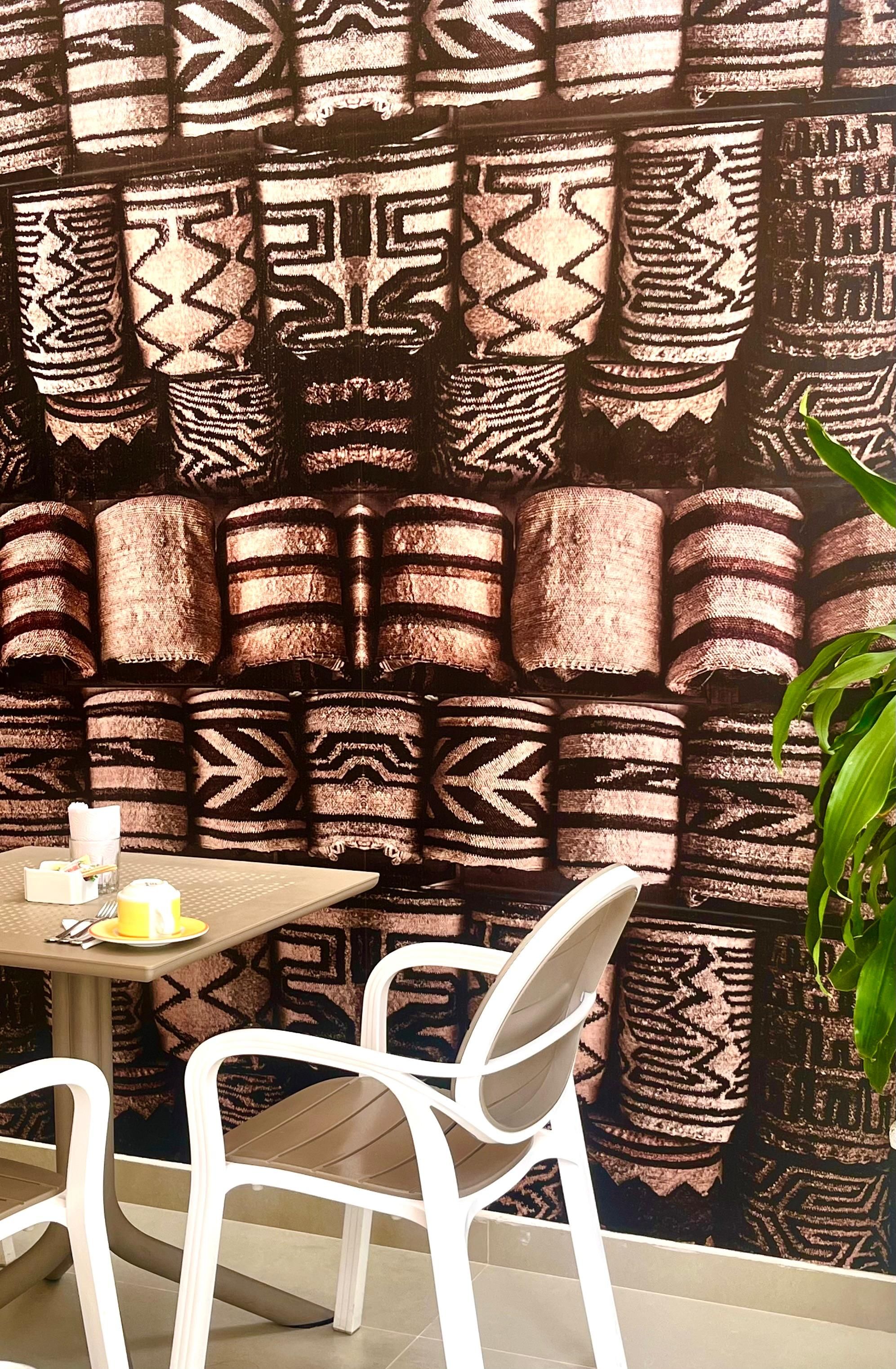 Una pared con diseño, una mesa con sillas y una planta en maceta.