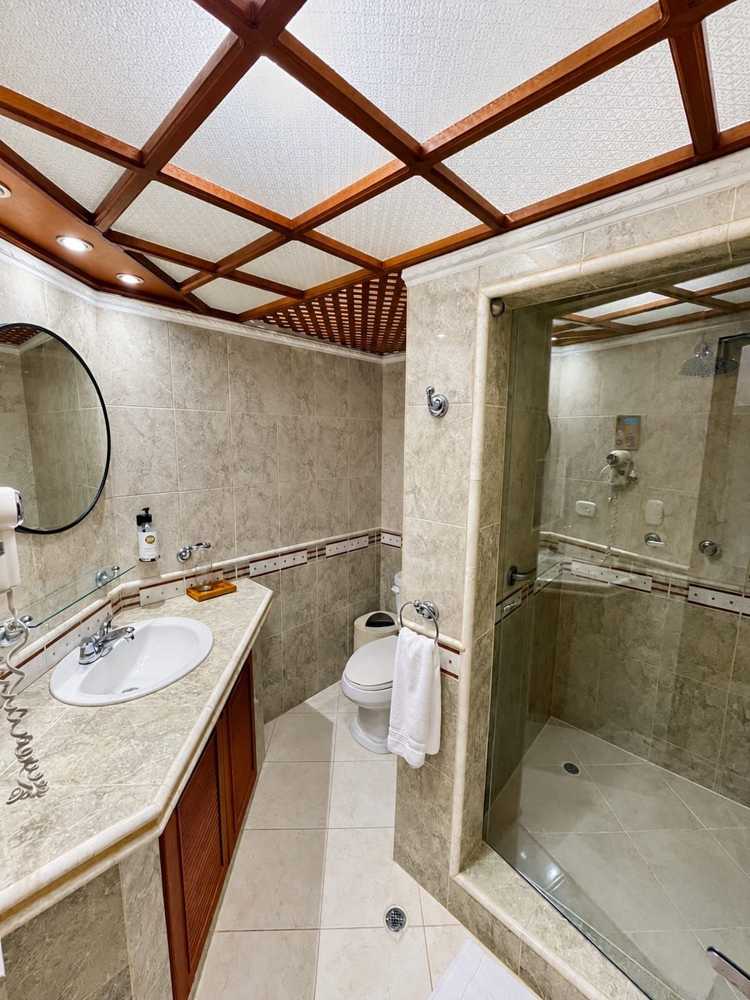 A bathroom with a glass-enclosed shower, a sink with a mirror, and a toilet.
