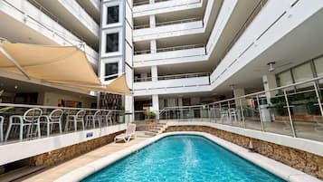 A multi-level indoor swimming pool with clear glass ceilings, multiple balconies, and a stone-lined pool edge.