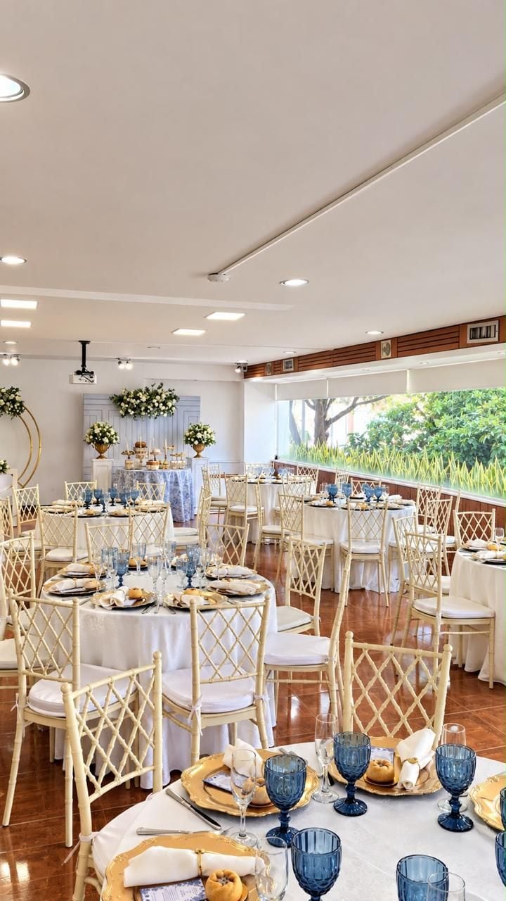 Un espace repas avec des tables rondes, des nappes blanches et de la verrerie bleue.