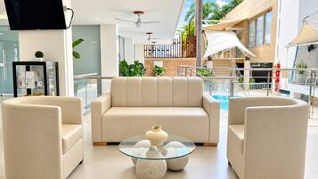 Una sala de estar moderna con un sofá, dos sillones y una mesa de centro de vidrio con objetos decorativos.