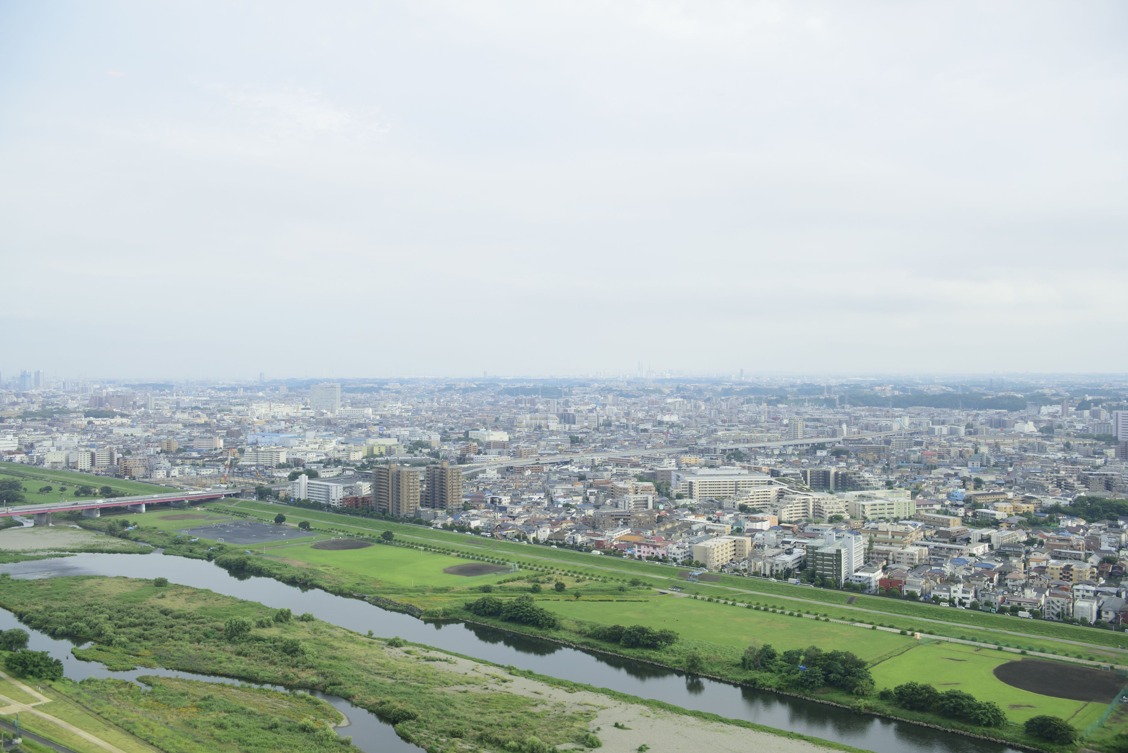 A cityscape with a river, green spaces, and a bridge.