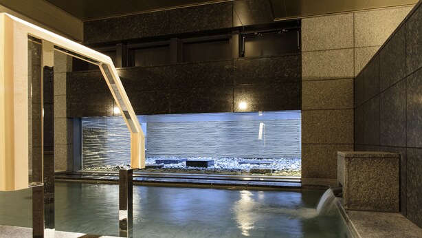 A modern spa area with a large water feature, stone walls, and a glass partition. - FutakoTamagawa Excel Hotel Tokyu (Tokyo)