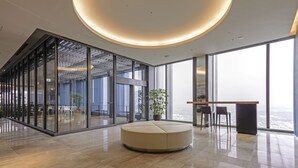 A modern interior with a circular seating area, large windows, and a view of the city. - FutakoTamagawa Excel Hotel Tokyu (Tokyo)