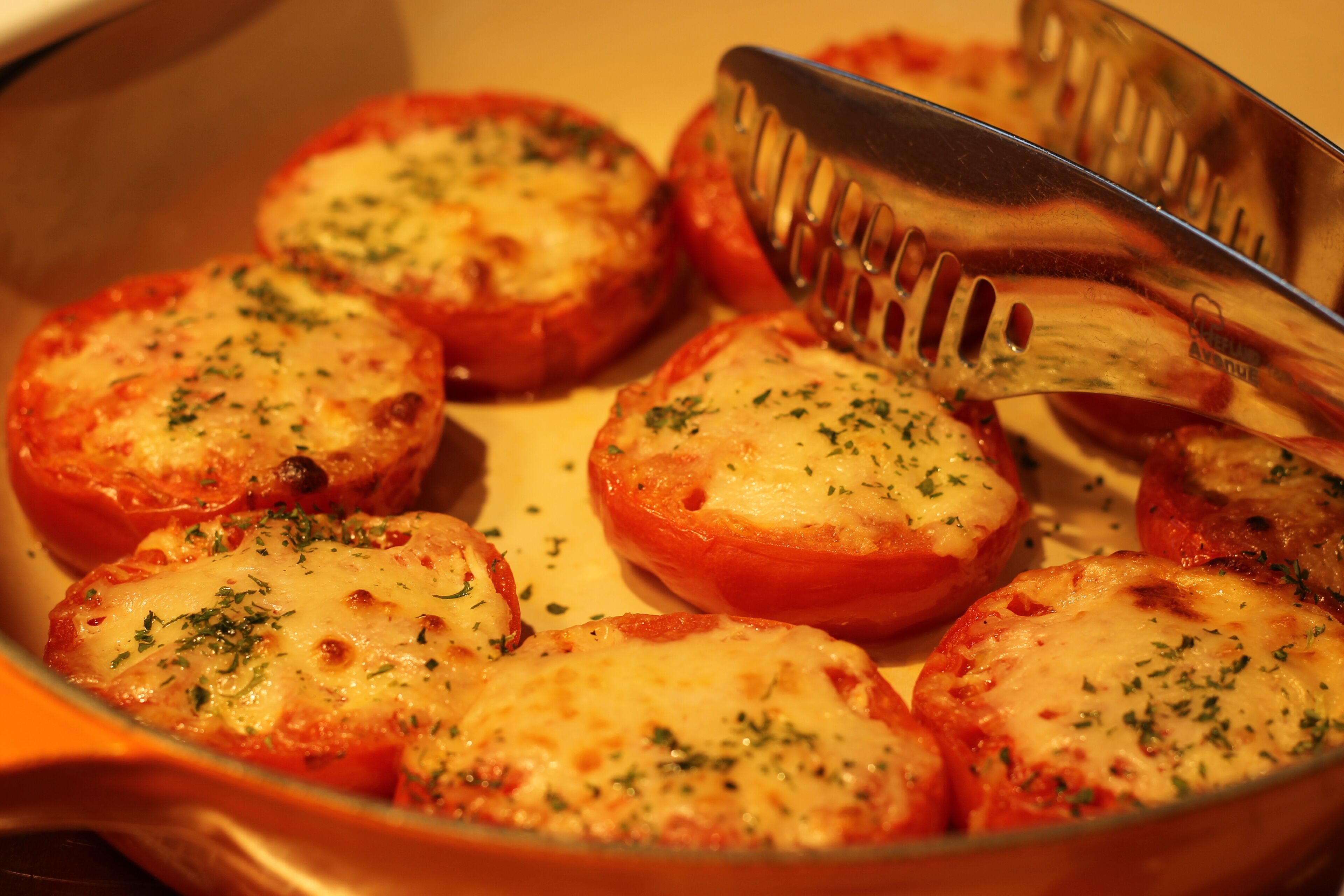 A dish of baked tomatoes with cheese and herbs.