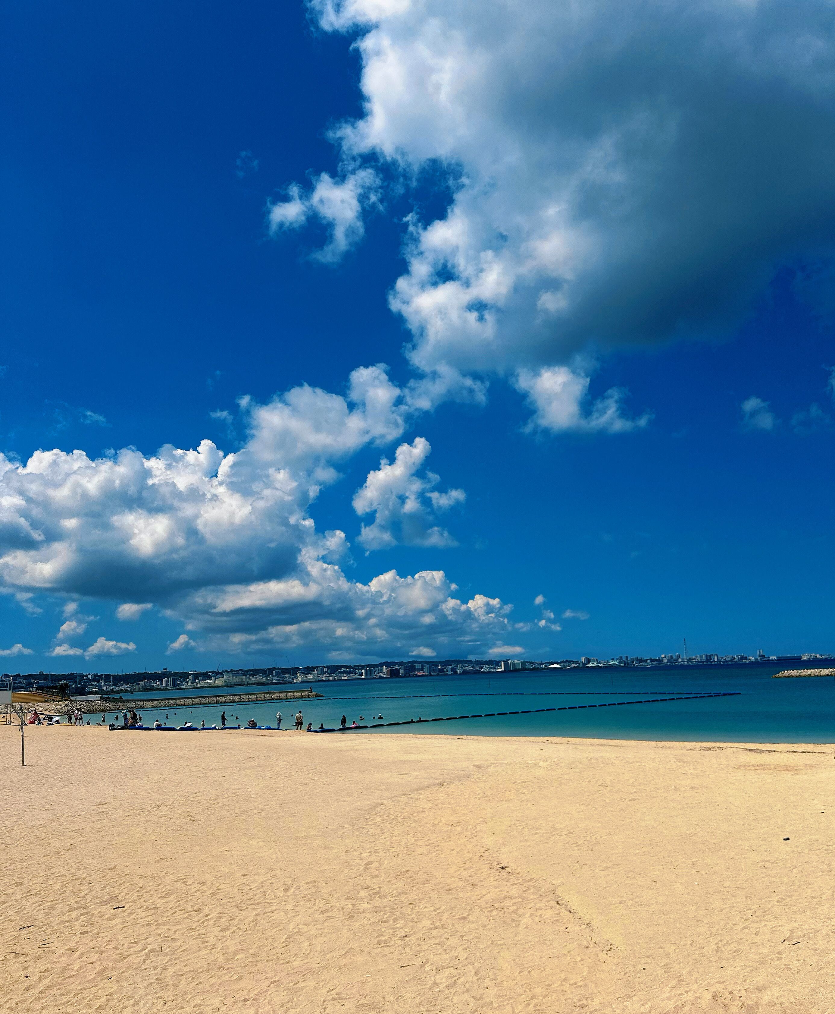 Een strand met een heldere lucht en een verafgelegen stadsbeeld.