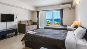 A hotel room with two beds, a TV, a desk, and a balcony with a view. - Condominium Hotel Monpa (Chatan)