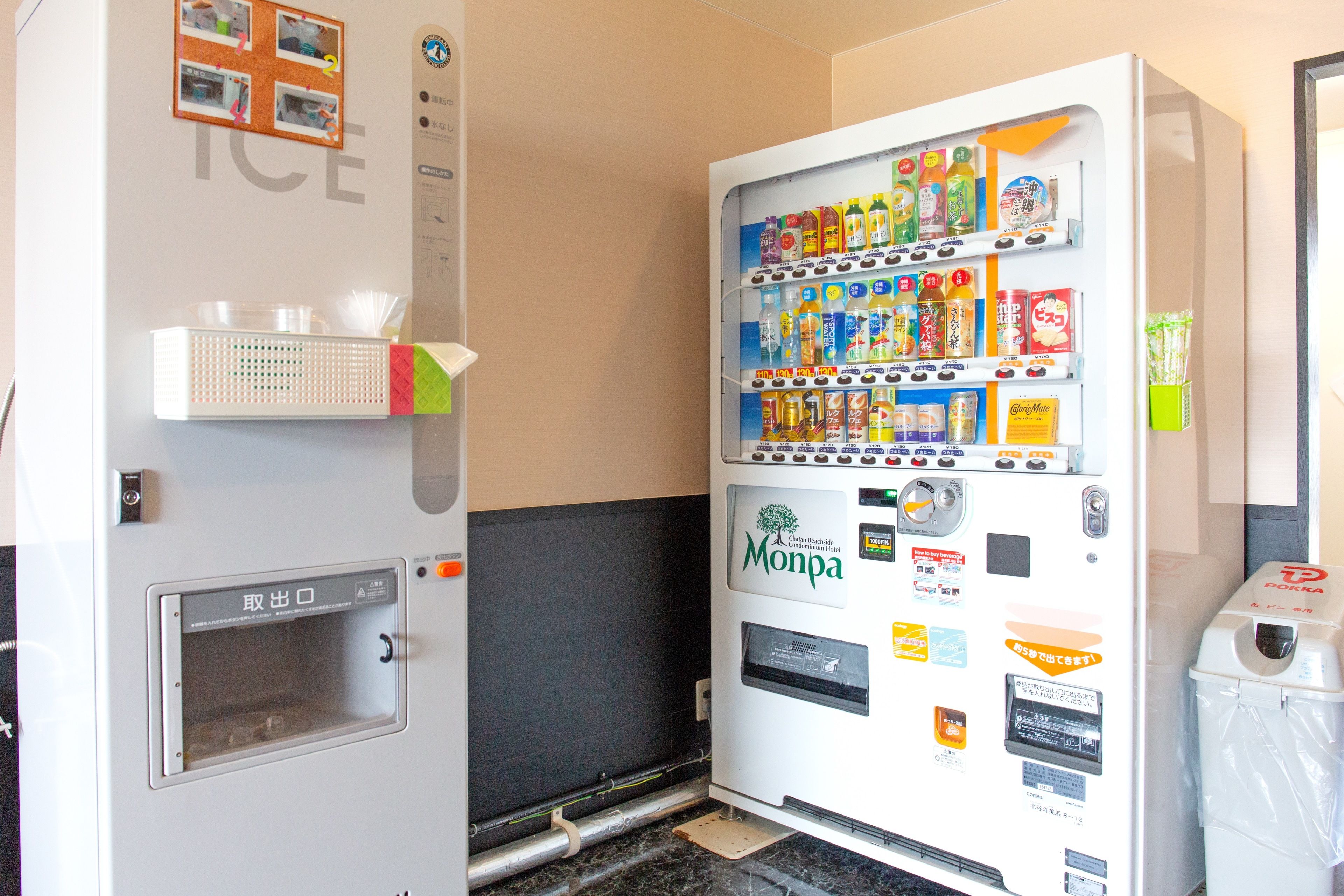 A vending machine with various beverages and snacks, a trash bin, and a small window with a handle.