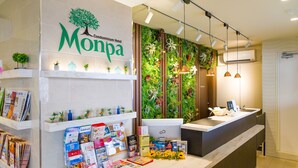A hotel reception area with a modern design, featuring a reception desk, a wall-mounted plant display, and various informational brochures. - Condominium Hotel Monpa (Chatan)