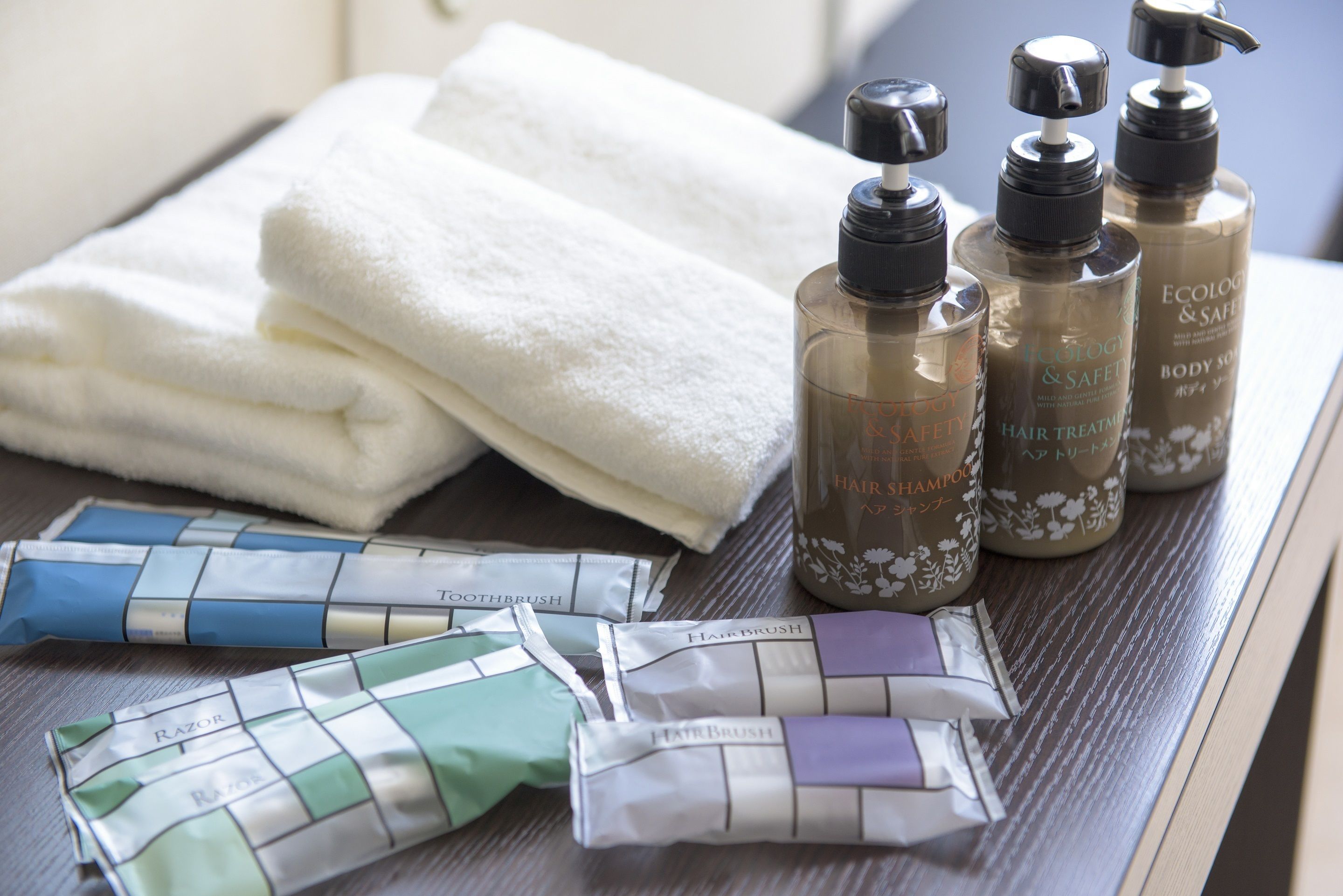 Toiletries including hair treatment, body soap, and razors on a wooden surface.