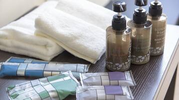 Toiletries including hair treatment, body soap, and razors on a wooden surface.
