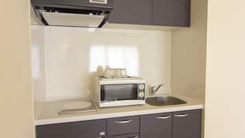 Una cocina compacta con microondas, un fregadero y un pequeño armario.